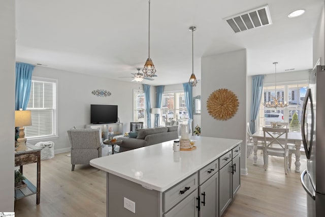 kitchen with hanging light fixtures, light hardwood / wood-style flooring, stainless steel refrigerator, and plenty of natural light