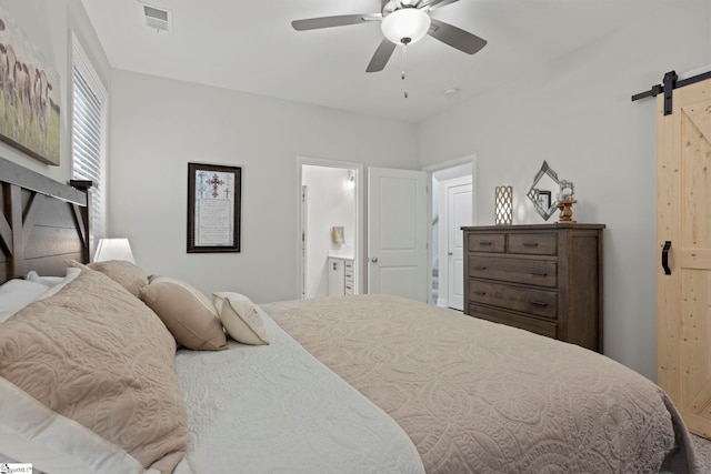 bedroom featuring a barn door, ceiling fan, and ensuite bath