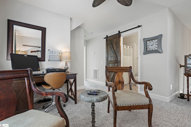 carpeted office with a barn door and ceiling fan