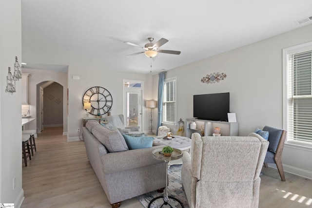 living room with a wealth of natural light, light hardwood / wood-style flooring, and ceiling fan