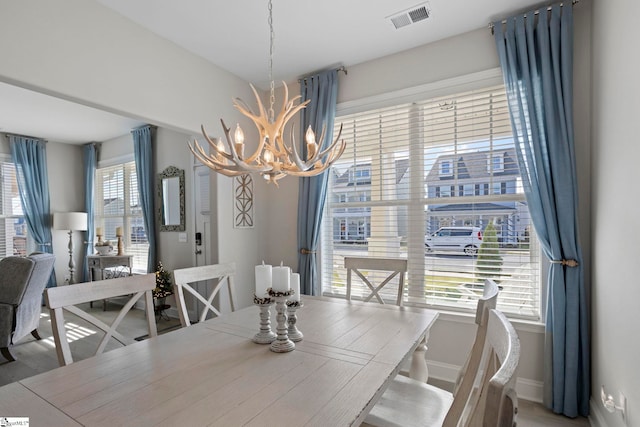 dining space with hardwood / wood-style floors, an inviting chandelier, and a wealth of natural light