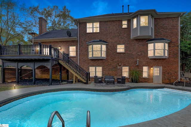 pool at dusk with a wooden deck