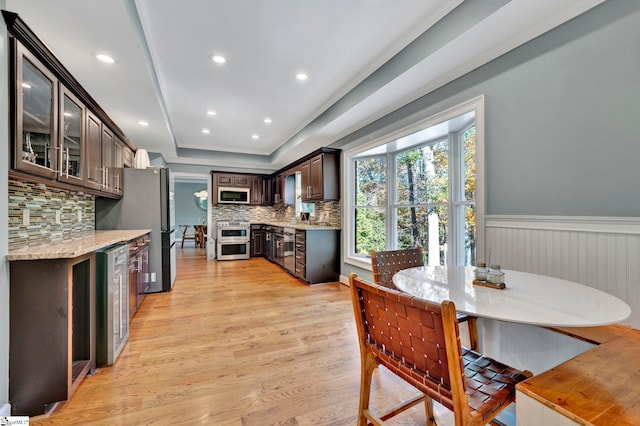 kitchen featuring decorative backsplash, appliances with stainless steel finishes, dark brown cabinetry, light hardwood / wood-style flooring, and wine cooler