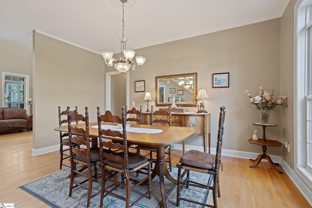 dining room with light hardwood / wood-style floors, ornamental molding, and an inviting chandelier