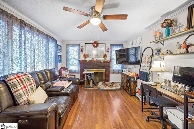 interior space with hardwood / wood-style floors, crown molding, a brick fireplace, ceiling fan, and a textured ceiling