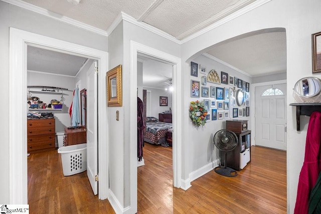 hallway with hardwood / wood-style floors, ornamental molding, and a textured ceiling