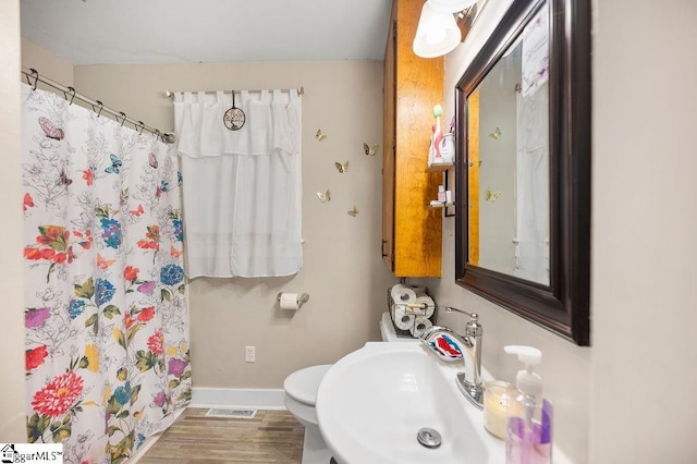 bathroom with a shower with curtain, sink, hardwood / wood-style floors, and toilet