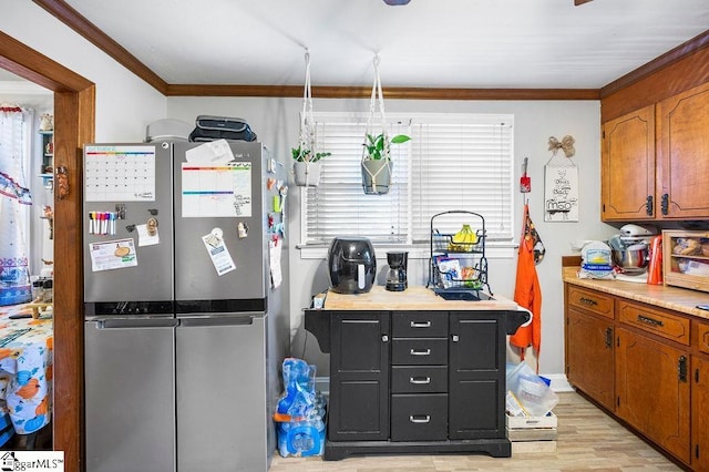 kitchen featuring stainless steel refrigerator, plenty of natural light, ornamental molding, and light wood-type flooring