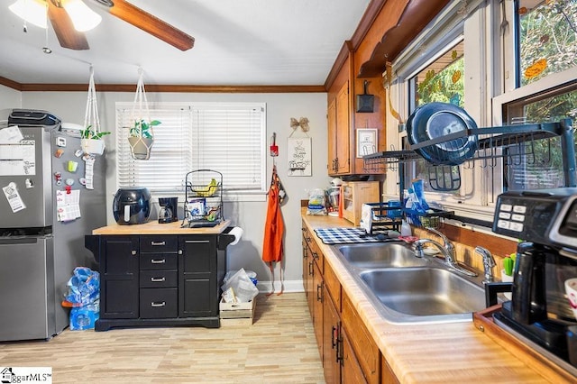 kitchen with stainless steel fridge, light wood-type flooring, ornamental molding, ceiling fan, and sink