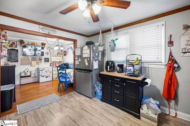 kitchen featuring ceiling fan, ornamental molding, stainless steel refrigerator, and light hardwood / wood-style flooring