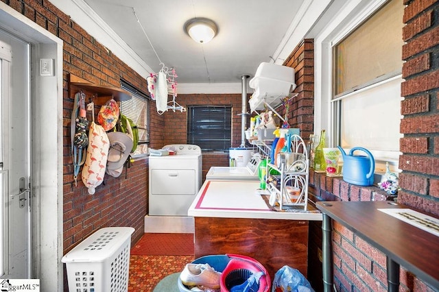 washroom featuring washing machine and dryer, crown molding, and brick wall