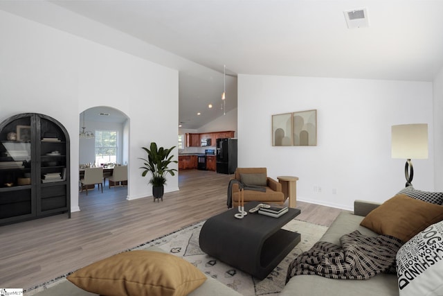 living room featuring high vaulted ceiling and light hardwood / wood-style flooring