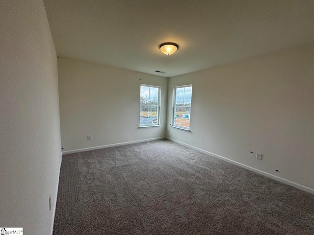 spare room with dark colored carpet