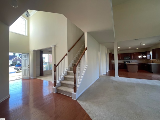 foyer entrance with a high ceiling, plenty of natural light, a notable chandelier, and hardwood / wood-style floors