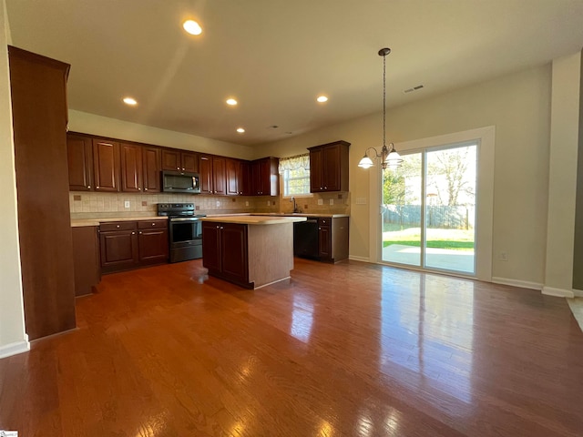 kitchen featuring a center island, dark hardwood / wood-style floors, backsplash, decorative light fixtures, and appliances with stainless steel finishes