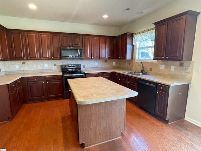 kitchen featuring backsplash, black appliances, sink, a kitchen island, and wood-type flooring