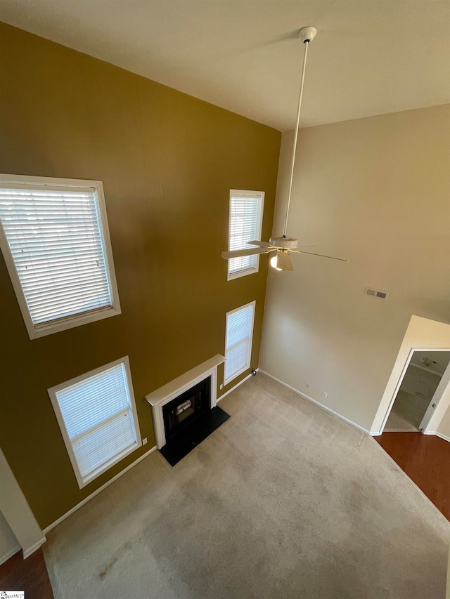 unfurnished living room featuring light colored carpet, high vaulted ceiling, and ceiling fan