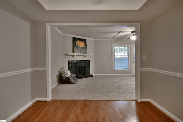 unfurnished living room with hardwood / wood-style floors, ceiling fan, and crown molding