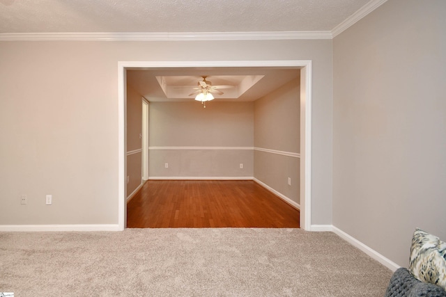 carpeted spare room with a raised ceiling, ceiling fan, crown molding, and a textured ceiling