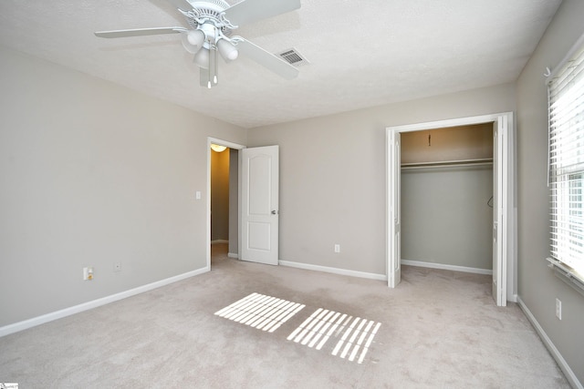 unfurnished bedroom featuring ceiling fan, a closet, light carpet, and a textured ceiling