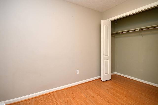 unfurnished bedroom with light hardwood / wood-style floors, a textured ceiling, and a closet