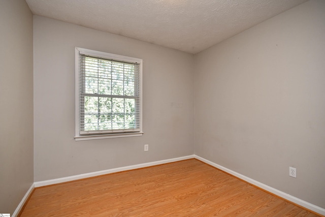 spare room with a textured ceiling and light wood-type flooring