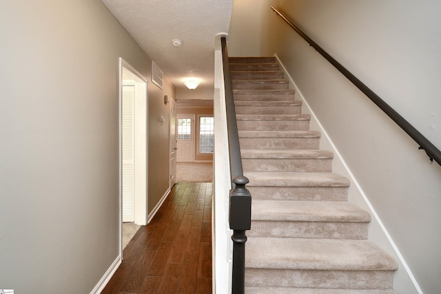 stairs featuring hardwood / wood-style flooring and a textured ceiling