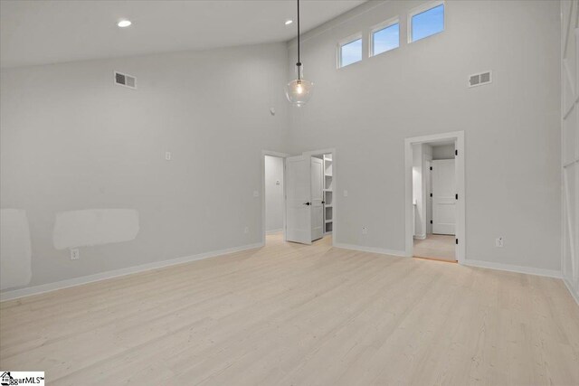 unfurnished room featuring high vaulted ceiling and light hardwood / wood-style flooring