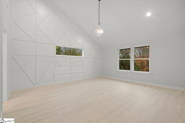 spare room with light hardwood / wood-style flooring and vaulted ceiling