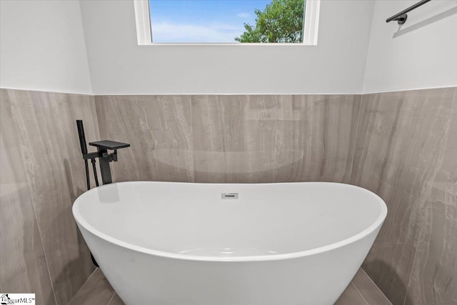 bathroom with a bathtub and tile walls