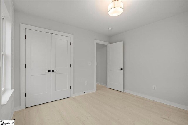 unfurnished bedroom featuring light hardwood / wood-style flooring and a closet