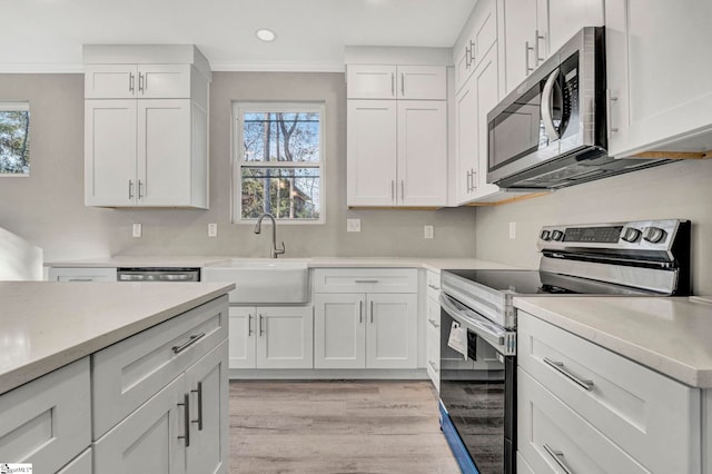 kitchen with stainless steel appliances, white cabinetry, and sink