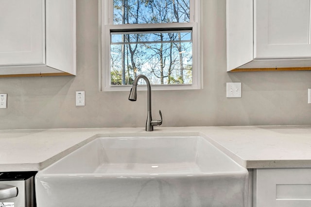 room details featuring light stone countertops, sink, and white cabinets