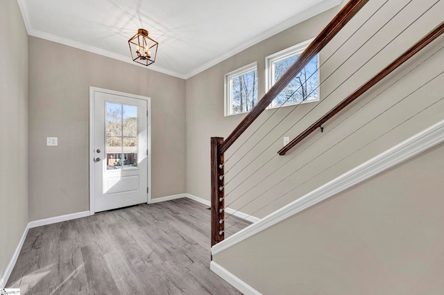 entryway with light wood-type flooring, crown molding, a wealth of natural light, and an inviting chandelier