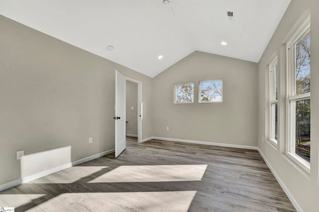 unfurnished room featuring plenty of natural light, lofted ceiling, and light hardwood / wood-style flooring