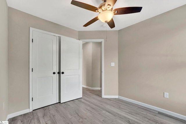 unfurnished bedroom featuring ceiling fan, a closet, and light wood-type flooring