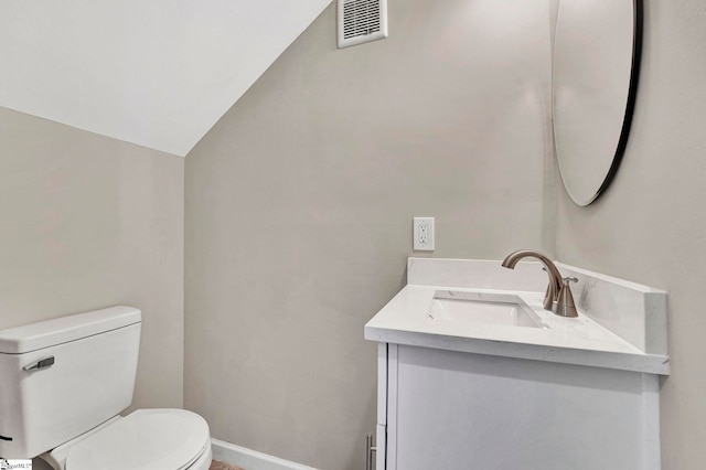 bathroom with vanity, toilet, and lofted ceiling