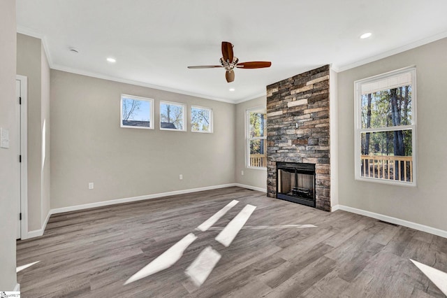 unfurnished living room featuring a stone fireplace, a wealth of natural light, and light hardwood / wood-style flooring