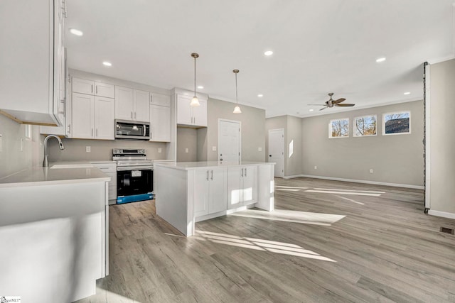 kitchen with pendant lighting, sink, a kitchen island, white cabinetry, and stainless steel appliances