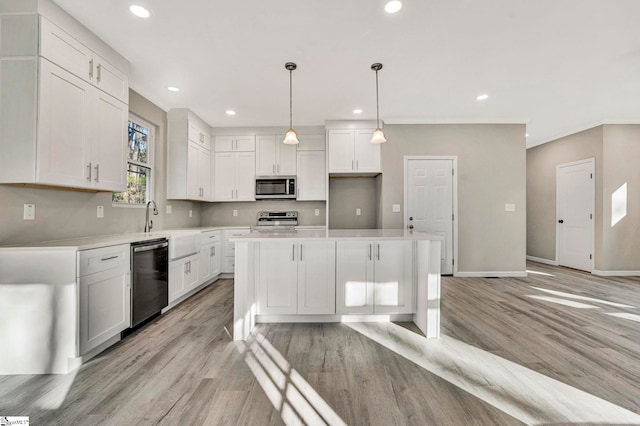 kitchen with white cabinets, appliances with stainless steel finishes, a kitchen island, and pendant lighting