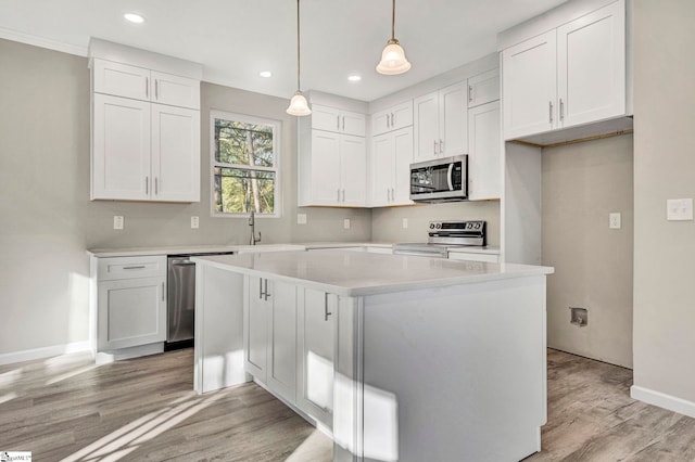 kitchen with a center island, white cabinets, light hardwood / wood-style flooring, decorative light fixtures, and stainless steel appliances