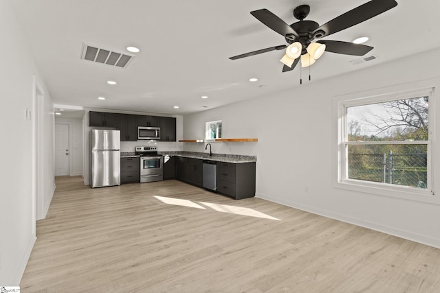 kitchen featuring light stone countertops, stainless steel appliances, ceiling fan, sink, and light hardwood / wood-style floors