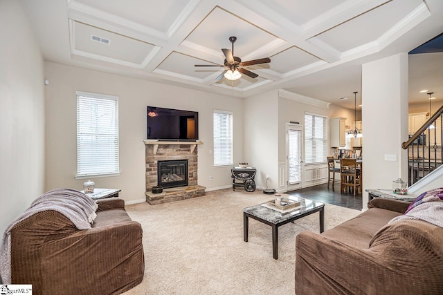 carpeted living room featuring beamed ceiling, ceiling fan, coffered ceiling, and a stone fireplace