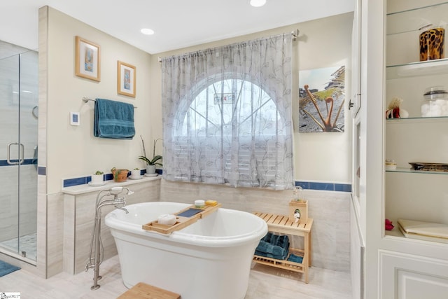 bathroom featuring plus walk in shower and tile walls