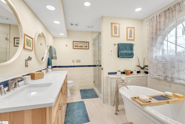 full bathroom featuring vanity, toilet, tile walls, and independent shower and bath