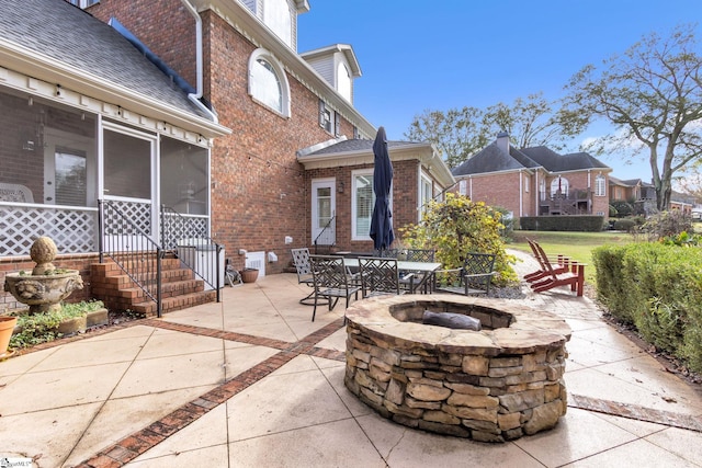 view of patio / terrace with a sunroom and a fire pit