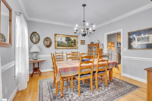 dining space featuring light hardwood / wood-style floors, ornamental molding, a wealth of natural light, and an inviting chandelier