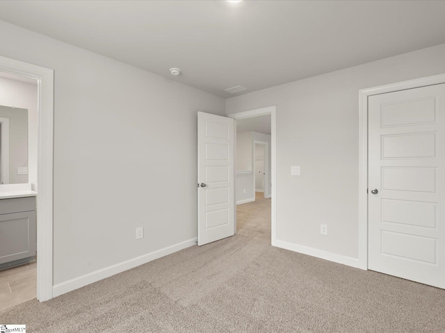 unfurnished bedroom with light colored carpet and ensuite bath