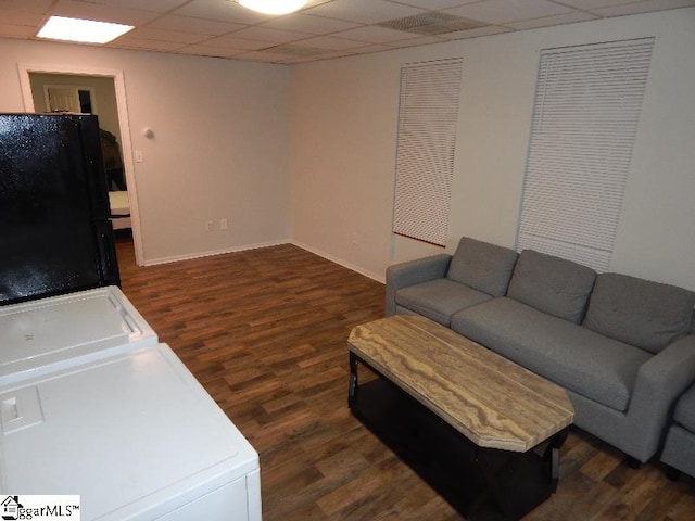 living room featuring a paneled ceiling, dark hardwood / wood-style floors, and washer / clothes dryer