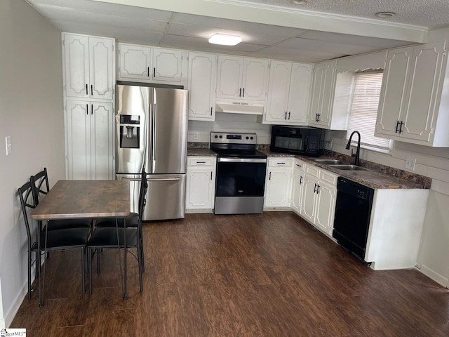 kitchen featuring a paneled ceiling, black appliances, sink, dark hardwood / wood-style flooring, and white cabinetry